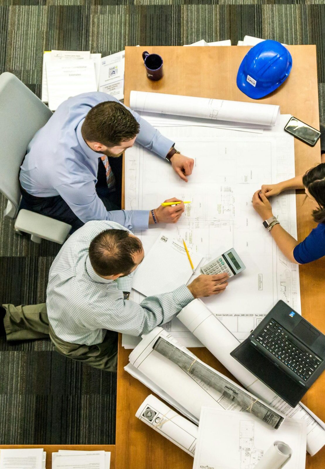 Top view of a team working on construction plans in an office setting.